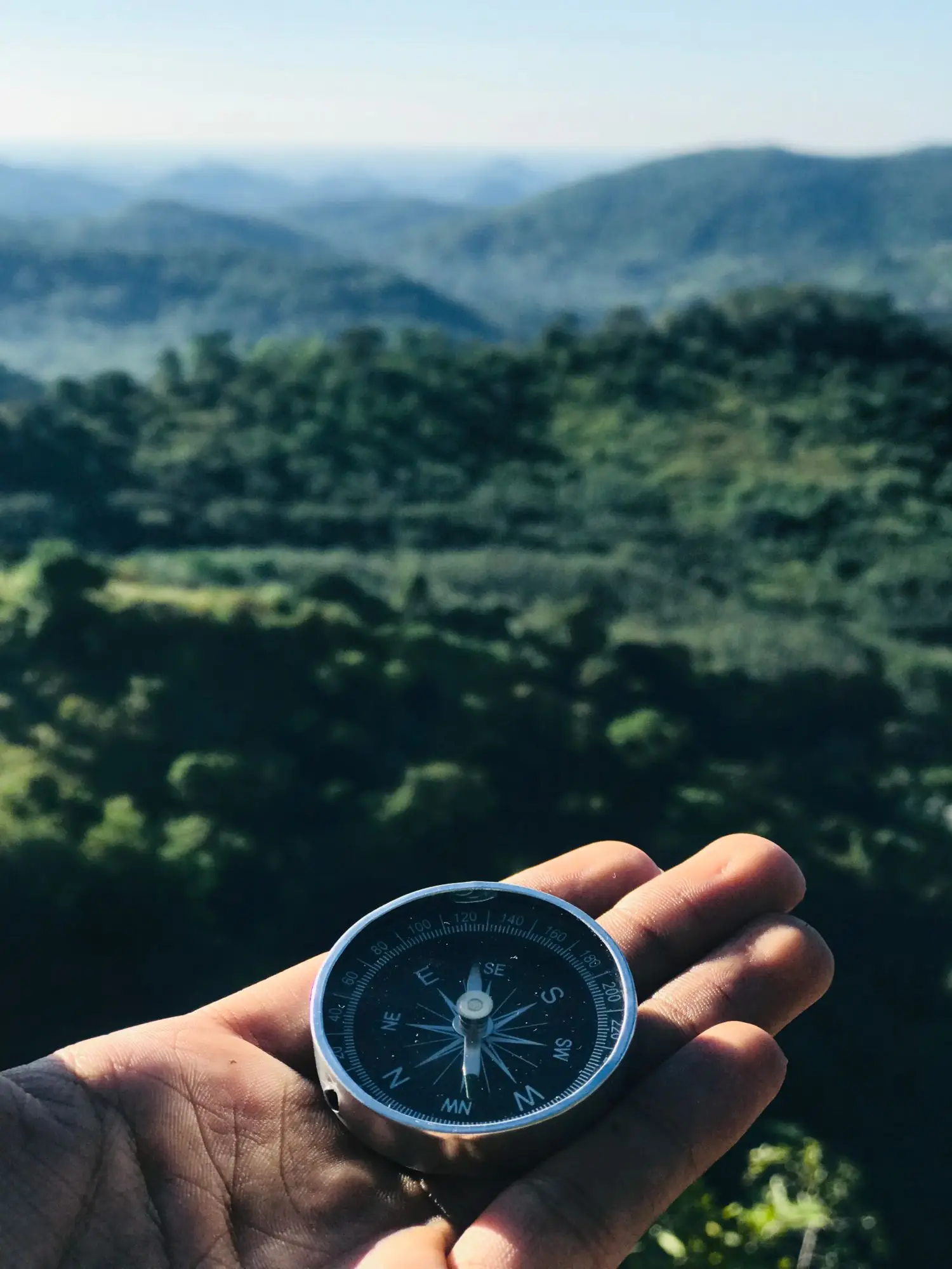 Compass held above a mountain landscape
