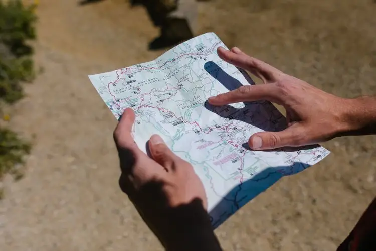 Hands reading a folded terrain map outdoors